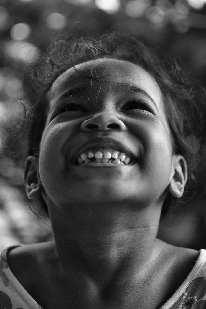 A young girl looking up and smiling from ear to ear, showing happiness and joy. 
